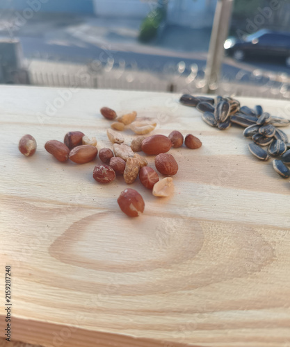 Peanuts and sunflower seeds arranged on a wooden board top view