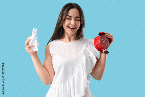 Angry businesswoman with alarm clock and crumpled paper on blue background. T...
