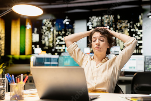 Bild auf Leinwand Demotivated businesswoman sighs and pushes her limits late at night, troubled by workload and life choices while struggling with fatigue and a mental haze
