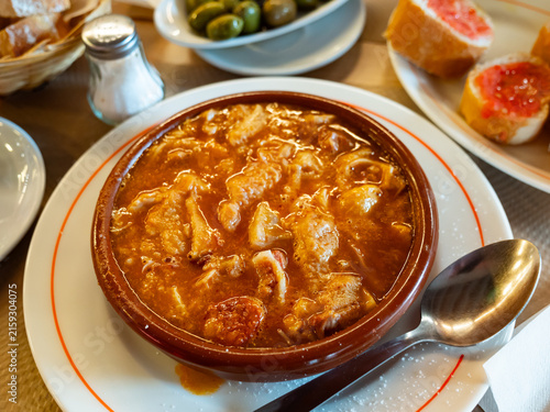 Beef stomach stew, potatoes, seasonings, tomato sauce. Traditional dish of Russian cuisine prepared in national restaurant for guests of institution, served in clay tureen with slices of bran bread