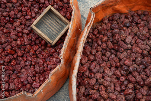 Quadro su tela Dried jujube red dates daechu filled in orange sacks with a wooden measure at a market in Korea