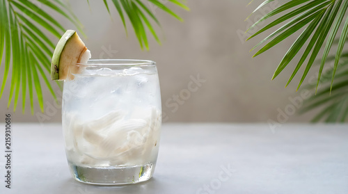Young coconut ice is served in a clear glass against a gray background with space for text.