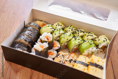 Foto Assorted sushi rolls arranged on in a box, featuring maki rolls with salmon, tuna, tamago surimi, avocado, lettuce, cucumber and other vegetable fillings
