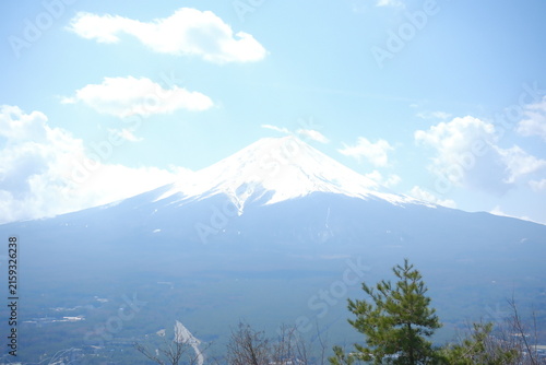 Snow capped Mount Fuji peak under a bright blue sky with fluffy white clouds in Japan.