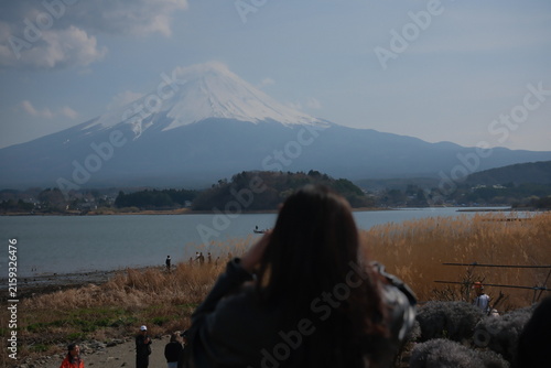 Woman photographing Mount Fuji from Lake Kawaguchi shore in Japan