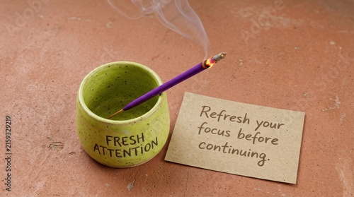Handmade purple incense stick burning in a green ceramic cup beside a note reading refresh your focus before continuing, providing a calming atmosphere perfect for mindfulness and mental rejuvenation.