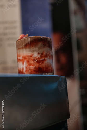 Layered strawberry milk drink in a glass on a dark counter