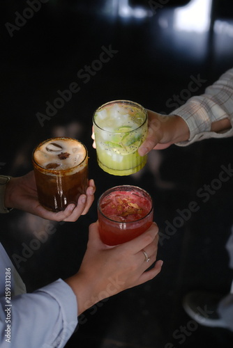 Hand squeezing fresh lime into vibrant cocktail with ice and citrus garnish on dark bar