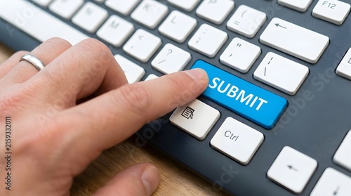 Close-up of finger pressing blue submit key on keyboard for online data entry and form submission