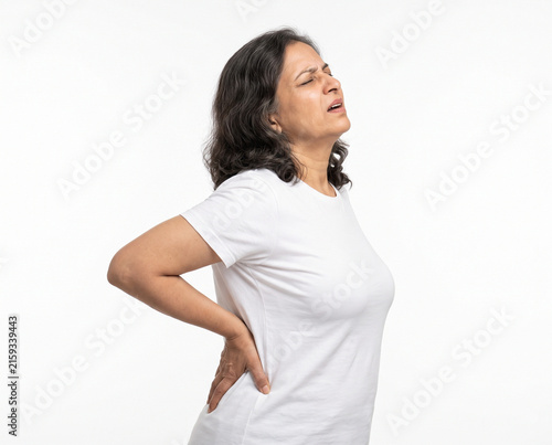 Senior Indian woman experiencing intense lower back pain and severe lumbar discomfort for physiotherapy chiropractic orthopedic healthcare aging wellness and pain management