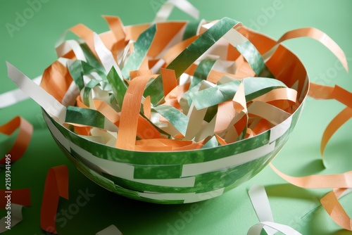 Striped paper bowl with orange and green streamers on green background