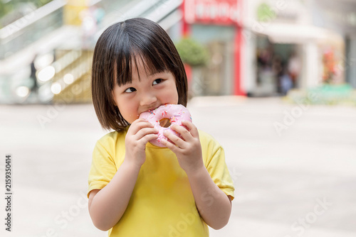 Obraz na płótnie Happy Little Asian Girl Eating Pink Glazed Donut with Crumbs on Face, Sweet Snac