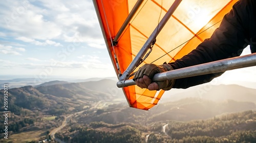 Tapety artystyczne Pilot's hand gripping hang glider control bar over mountainous landscape at sunset