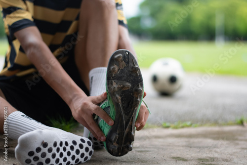 Close-up of a soccer player holding a football boot showing cleats sole and anti-slip grip socks on the ground.