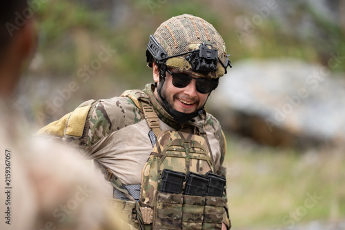 Obraz na plátne Young military soldier is smiling during field operation in dangerous battlefiel