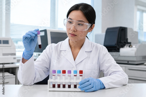 Scientist Holding Blood Sample Tube in Clean Laboratory Environment