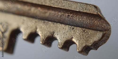 A closeup view of the worn, metallic teeth on an old skeleton key.