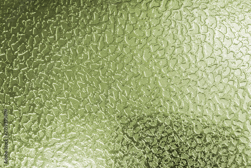 Abstract green silver metallic background featuring a shiny, reflective surface with an irregular hammered texture, subtle highlights, and soft shadows, creating a modern industrial background.