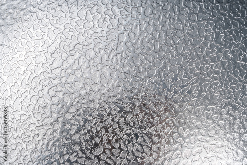 Abstract silver metallic background featuring a shiny, reflective surface with an irregular hammered texture, subtle highlights, and soft shadows, creating a modern industrial background.