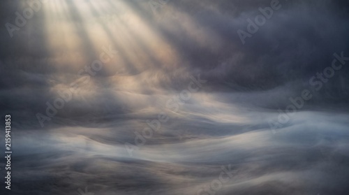 Dramatic sunbeams piercing through dense morning fog over misty landscape