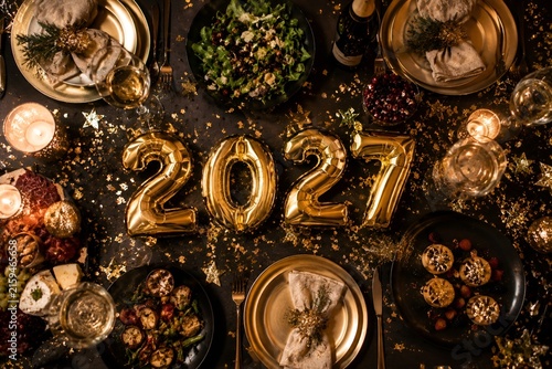Gold 2027 balloons on a festive dinner table for a New Year celebration party.