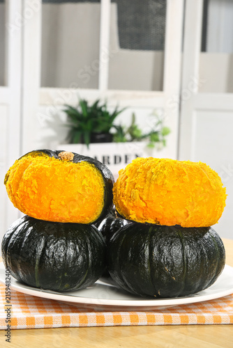 Fresh Kabocha Pumpkin Cut in Half Showing Orange Flesh on White Plate in Modern Kitchen Still Life Photography