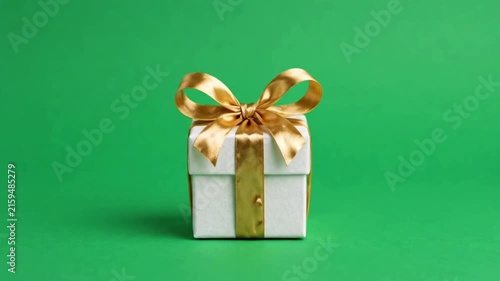 Realistic white gift box with ribbon on green background.