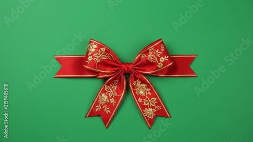 Realistic red bow on green background.