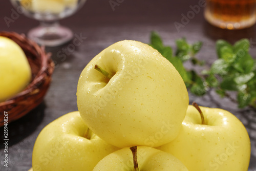 Fresh Golden Yellow Apples Cut to Show Pulp with Mint Leaves on Dark Kitchen Counter