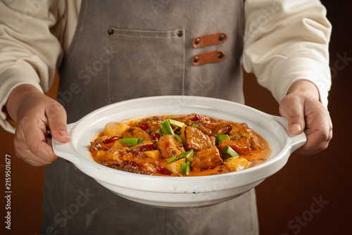 Chef Serving Woodfired Goose Stew in Traditional Ceramic Pot with Asian Spices and Garnish