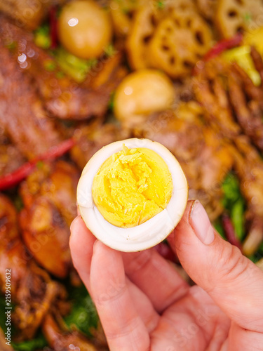 Foto Hand Holding Hard-Boiled Egg Half Over Asian Stir-Fry Dish with Vegetables and M