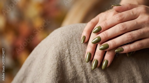 Close-up of Well-Groomed Hands with Olive Green Nail Polish on Beige Fabric