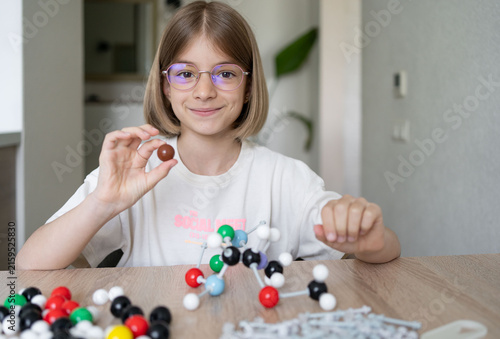 child constructing molecular model for science lesson, home education