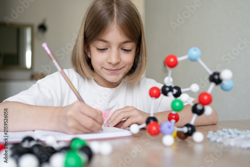 Young girl scientist studying molecular model in a home, carefully examining the structure. STEM education