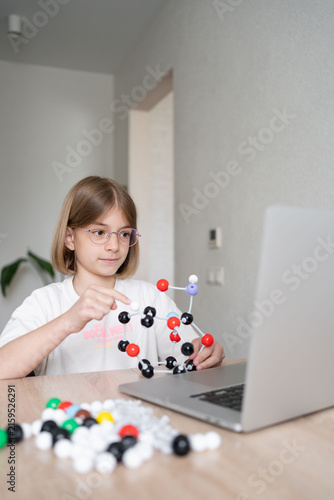 STEM education. The girl is focused on the molecular model. Science education at hone. Child studying chemistry online. 