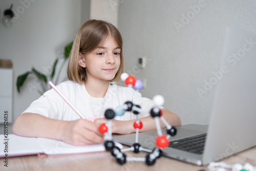STEM education. The girl is focused on the molecular model. Science education at hone. Child studying chemistry online. 