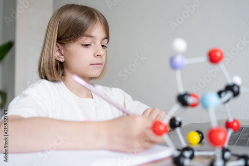 child girl assembling molecular model by learning from home with school teacher, teaching online, home education. Homeschool kid practicing chemistry and physics