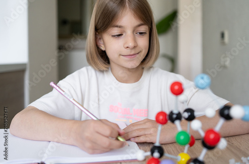 Young girl scientist studying molecular model in a home, carefully examining the structure. STEM education