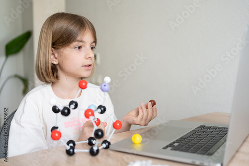 STEM education. The girl is focused on the molecular model. Science education at hone. Child studying chemistry online. 