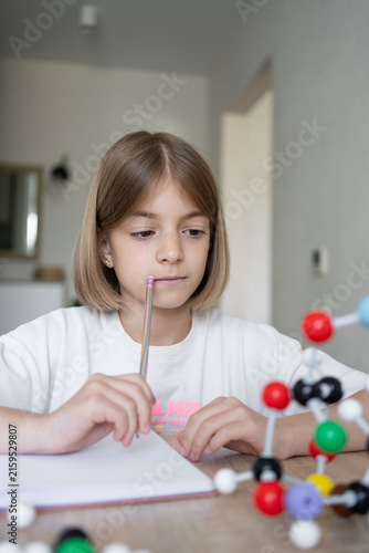 Young girl scientist studying molecular model in a home, carefully examining the structure. STEM education