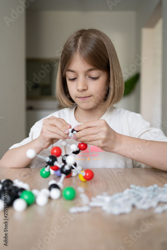 Young girl scientist studying molecular model in a home, carefully examining the structure. STEM education