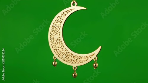 Elegant golden crescent moon ornament with intricate patterns, perfect for Ramadan and Eid celebrations, isolated on a vibrant green screen background for easy keying