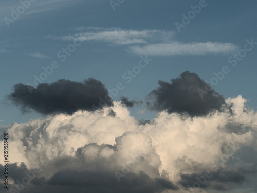Dynamic clouds featuring bright white cumulus bases overlaid with darker cloud fragments ranging from slate gray to near-black.