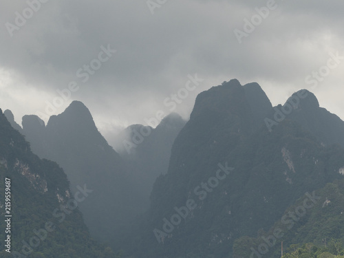 Ratchaprapha Dam on a rainy day at khao sok national park, surat thani province thailand featuring spectacular limestone mountains shrouded in mist.
