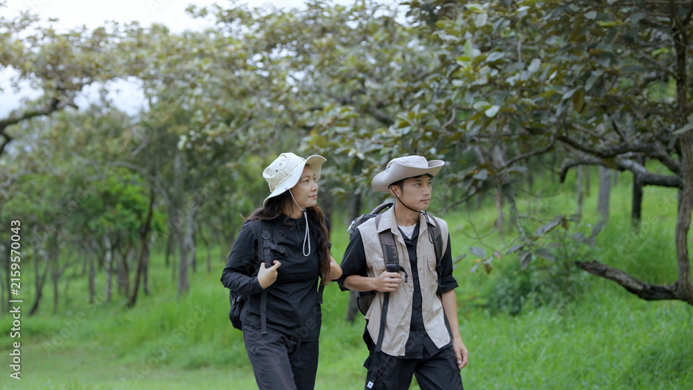 Fototapeta premium Young Couple Hiking Through Green Forest During Nature Travel Adventure