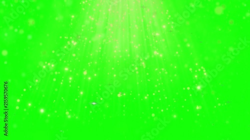 Golden light rays and glowing dust particles stream downward against a bright green screen background.
