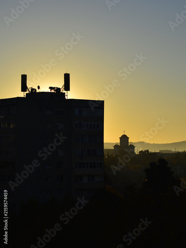 Silhouette of a building at dawn, with its antennas and air-raid sirens in Eastern Europe.