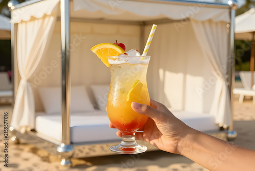 Hand holding an iced tropical drink with fresh fruit garnish beside a luxury beach cabana, chrome accessories, Y2K vacation vibe, warm golden sunlight, premium commercial photography, no branding.