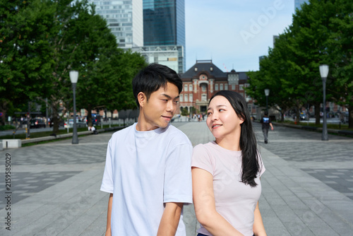 Young Japanese Man and Woman Standing Together on City Street, Gazing at Each Other