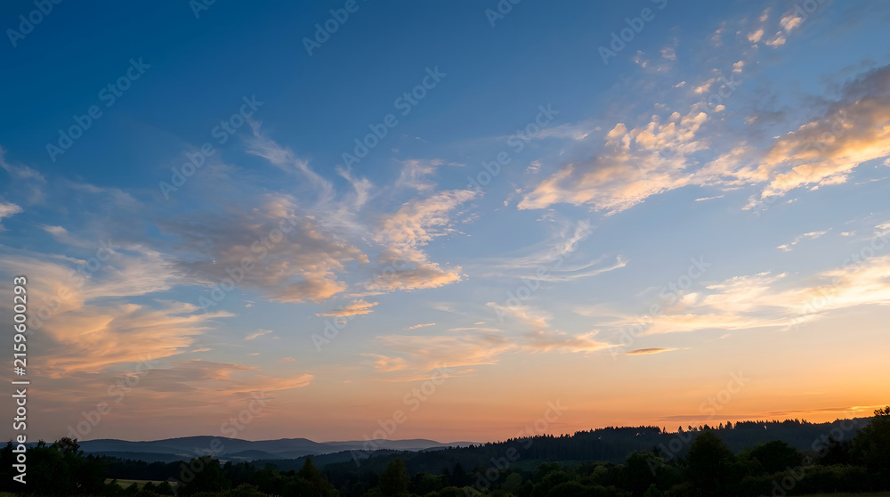 Fototapeta premium Vast sky painted with sunset hues over rolling hills.